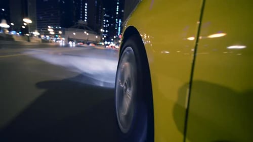 Yellow Car Wheel Spins Through City Night