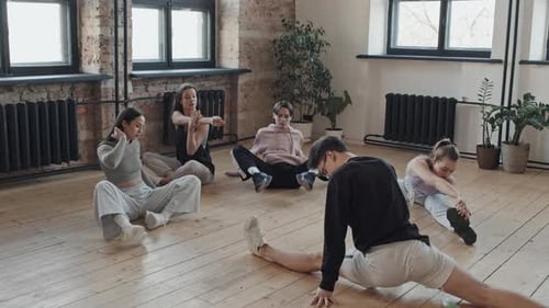 Young Adults Stretching Together in Bright Studio