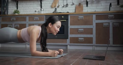 Woman Exercising with Laptop in Her Kitchen