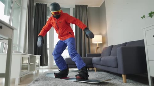 Fun Video. Man Dressed As a Snowboarder Rides a Snowboard on a Carpet in a Cozy Room. Waiting for a