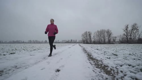 Woman Running on Snowy Path in Winter Landscape