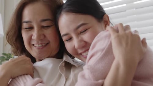 Asiatische Familie Mutter-Tochter umarmt Kuscheln auf dem Sofa zu Hause.