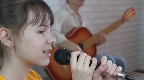 Girl Sings Into Microphone With Guitar Accompaniment
