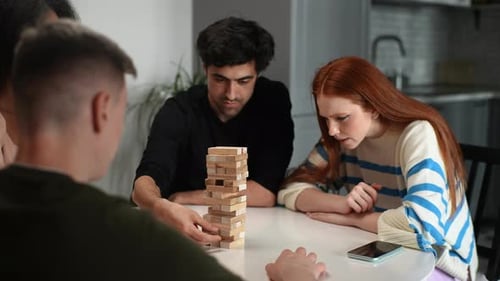 Group of Multiethnic Cheerful Friends Enjoying Game with Wooden Tower Blocks Playing Competition
