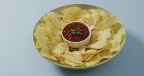 Primer plano de las patatas fritas en un bol con salsa sobre una superficie azul