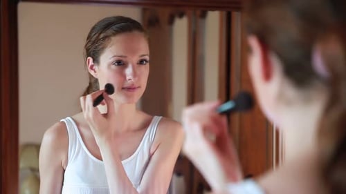 Woman Applies Makeup in Front of Mirror