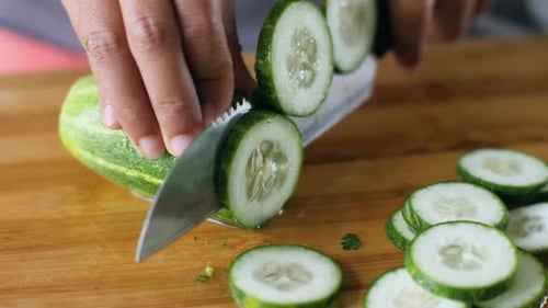 Slicing Fresh Green Cucumber on Cutting Board