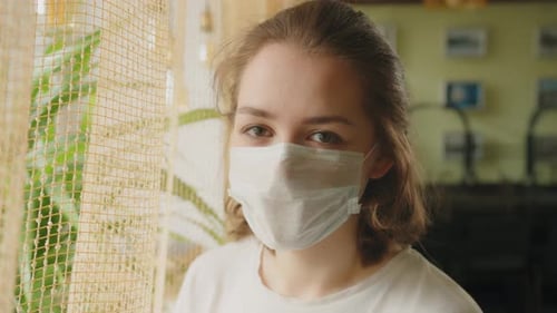 Woman in Medical Mask Standing Near Window