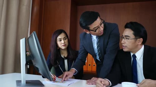 Geschäftsleute arbeiten zusammen am Schreibtisch und überprüfen einen Finanzbericht.
