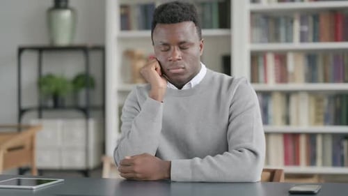 Sleepy African Man Taking Nap While Sitting in Library