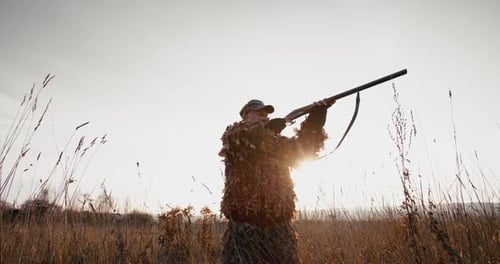 Jäger in Jagdausrüstung Zielen Sie mit dem Gewehr im Feld am nebligen Morgen oder am sonnigen Abend