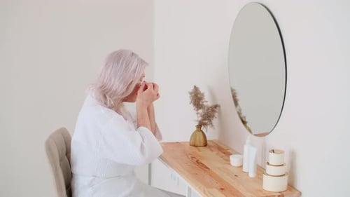 Senior Woman Applies Skincare Products at Vanity