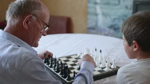 Lernspiele, ein älterer intelligenter Großvater spielt mit seinem geliebten gutaussehenden Enkel
