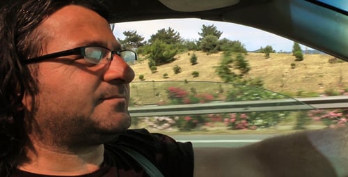 Man Driving Car on Highway, Mountains in Background