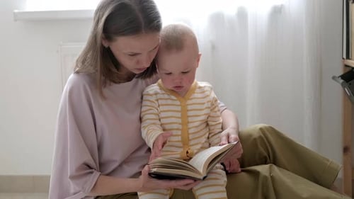 Mother Reading Book with Baby at Home