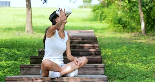 Woman watching with virtual reality device and sitting at the park