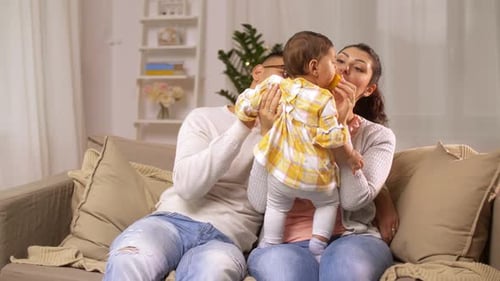 Madre, padre y bebé comiendo naranja en casa
