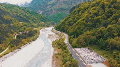 Flying Over a Mountain Winding Highway Near a Mountain Stream