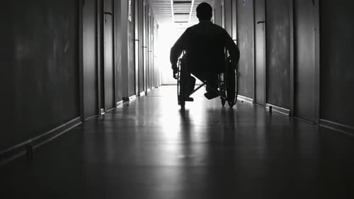 Silhouette of Man Riding on Wheelchair along Corridor