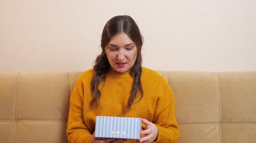 Woman Opens Gift with Disappointed Expression