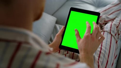 Person Using Tablet with Green Screen on Couch