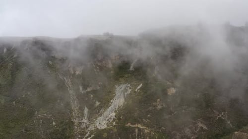 Aerial view that is heading towards a cliff while clouds cover the view