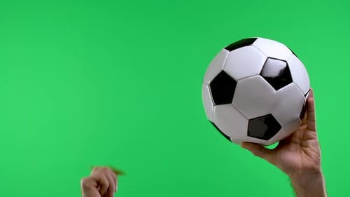 A Male Hand is Holding a Soccer Ball and the Second Hand is Showing a Red Card Isolated on a Studio