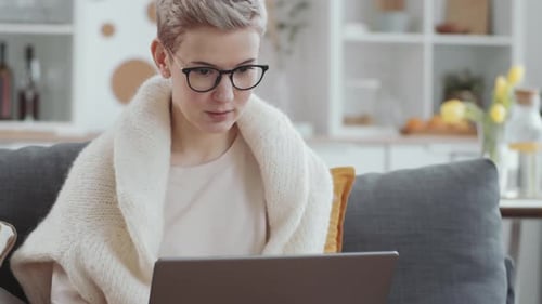 Woman working on laptop computer at home on couch