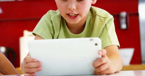 Child Plays with Tablet at Table Indoors