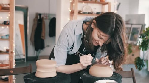 Woman Crafting Pottery in Brightly Lit Workshop
