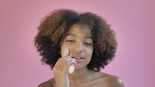 Woman Massaging Face with Pink Jade Roller
