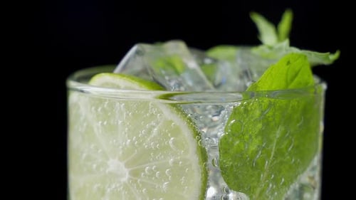 Mojito Cocktail Close-up. Glass of Alcohol Cocktail with Rum, Lime, Mint, Crashed Ice and Brown