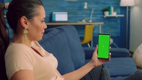 Woman holds phone with green screen indoors