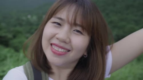 Hiker backpacker woman on hiking adventure feeling freedom walking in forest near lake in rainy day.