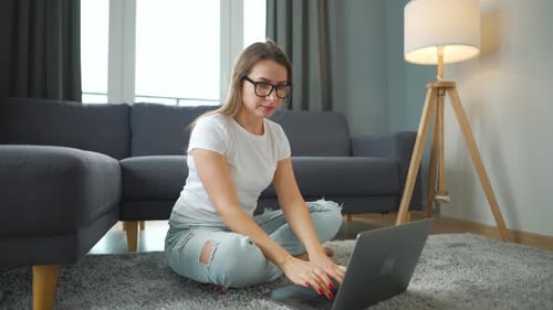 Woman Working on Laptop at Home on Floor