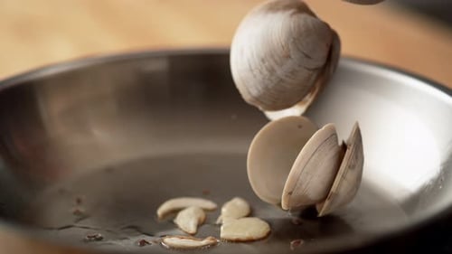 La caméra suit la cuisson des palourdes dans de l'huile d'olive avec de Ralenti.