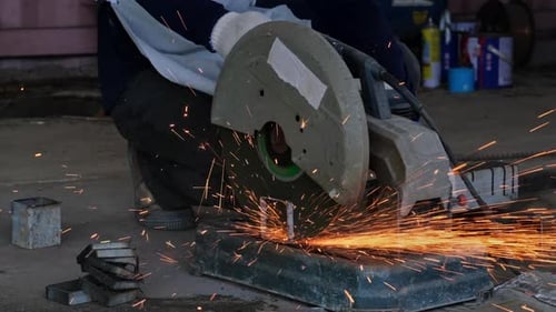 Worker Cuts Metal with Circular Saw with Sparks