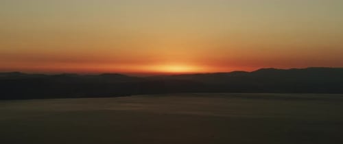 Beautiful landscape with sunset over the big lake and the mountains. Tilting down to up shot.