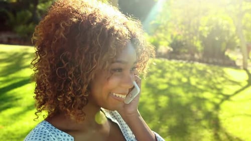 Smiling Woman Using Smartphone in Sunny Green Park