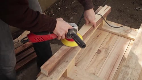 Person Sanding a Wood Plank with Electric Sander