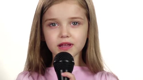 Child Girl Sings the Song Into the Microphone. White Background. Close Up. Slow Motion