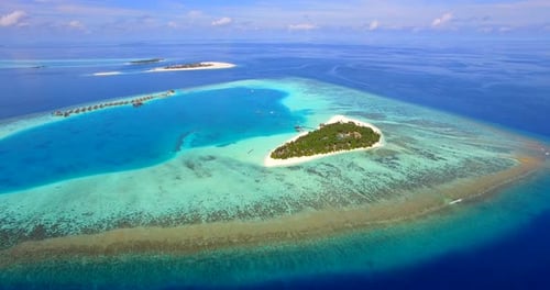 Aerial drone view of scenic tropical island and resort hotel with overwater bungalows in Maldives