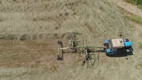 Trator com Rake Tedders no campo agrícola