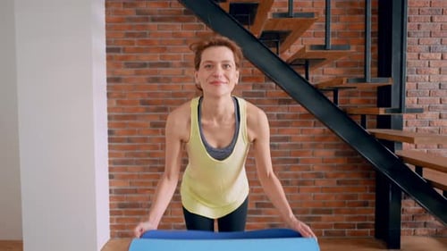 Woman Unrolls Yoga Mat in Modern Home