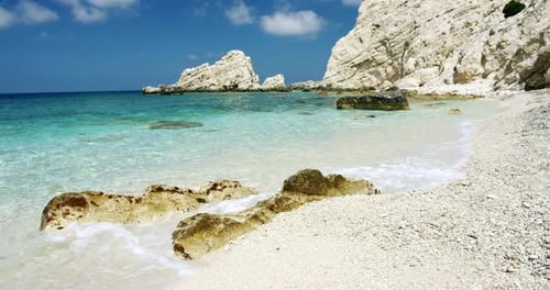 Clear Sea Waves Splashing on Peaceful White Beach with Pebbles Seascape with Rocks in Background