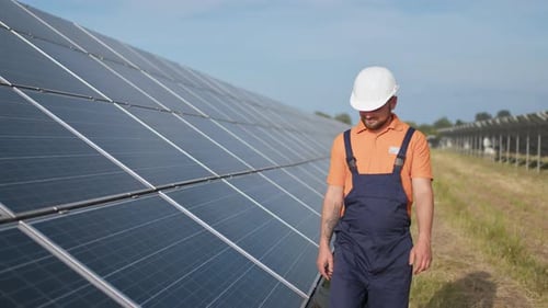 Männlicher Ingenieur in Uniform beim Gehen und Betrachten des Solarkraftwerks