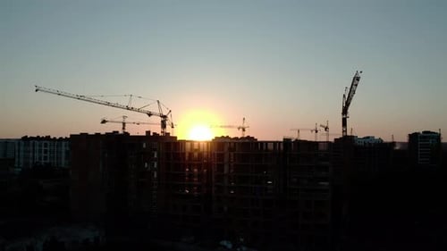 Aerial Drone View of Silhouette Construction Cranes in Sunset Light. Construction Site Building in
