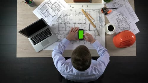 Developer Checking Information About House Construction on Green Screen Phone