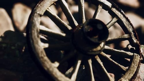 Old Weathered Wooden Cart Wheel Resting on Rocks