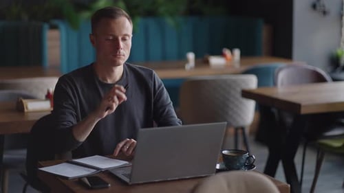 Smiling Man with Works From Home in His Kitchen Using a Laptop